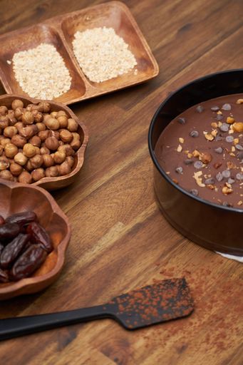 A vertical shot of a delicious chocolate tart with hazelnuts and dried palm fruits in a pan on the table