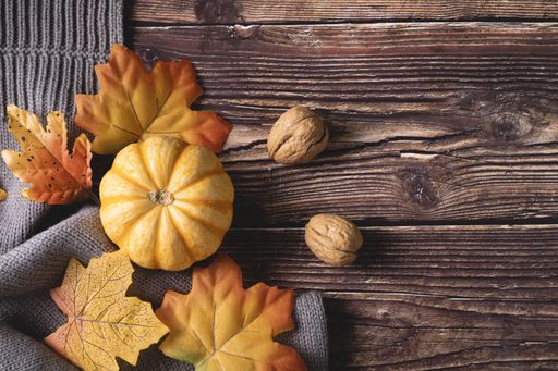 A top view of fresh pumpkins, walnuts, and autumn leaves on a wooden background