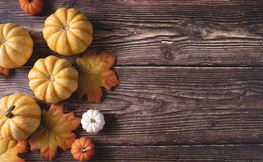 A top view of fresh pumpkins and autumn leaves on a wooden background