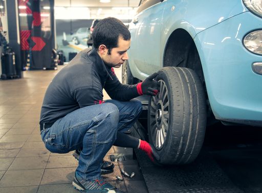 A young European mechanic working on a car tire in a garage