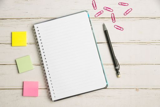 Keyboard Over A Table Beside A Notebook And Pens With Sticky Notes. Computer Keypad On Top Of A Desk With A Office Supplies And Desk Photo..