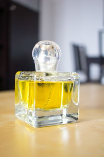 A vertical shot of a yellow perfume bottle on a table indoors