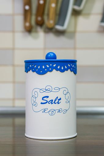 A vertical shot of a salt container, on a wooden table in the kitchen