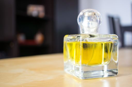 A macro shot of a yellow perfume bottle on a table indoors