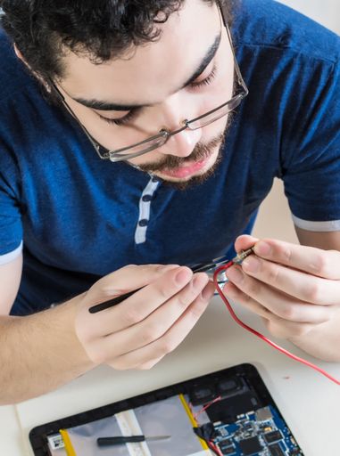 A computer repairman repairing components of electronic device
