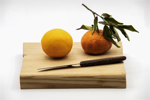 A shot of tangerine and orange on a wooden board with a knife on white background