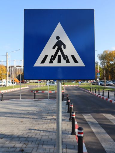 A vertical shot of the walking person sign on the road. Pedestrian road blue triangular sign
