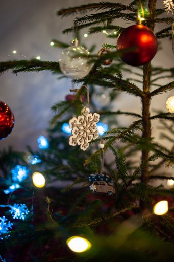 A vertical shot of a Christmas tree decorated with light garlands and colorful ornaments