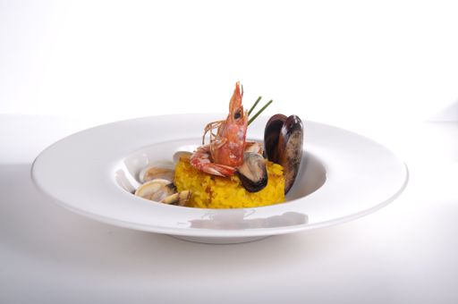 Isolated white plate with red king prawn and yellow rice. Paella