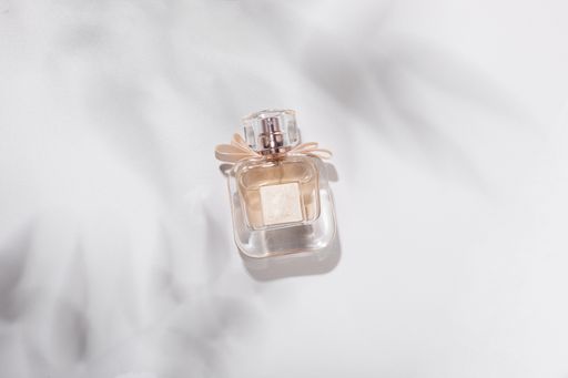 A top view of a bottle of perfume for the woman on a white cloth