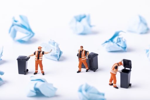 A selective focus shot of used paper and waste collector toys on a white background