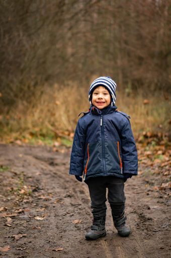 Young boy standing on a footpath in a forest of the Morasko park.