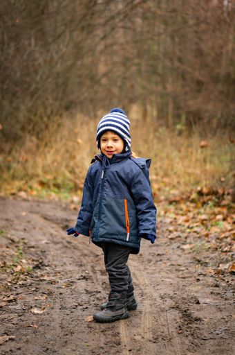 Young boy standing on a footpath in a forest of the Morasko park.