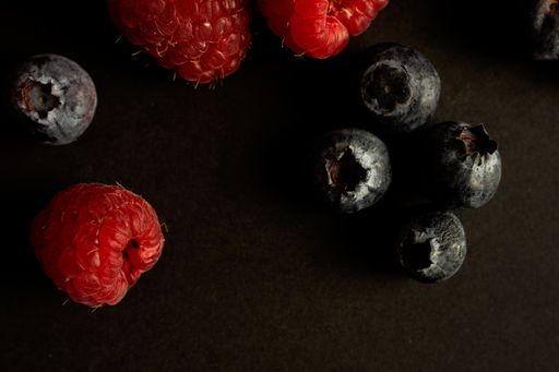 A closeup shot of fresh raspberries and blueberries on black background