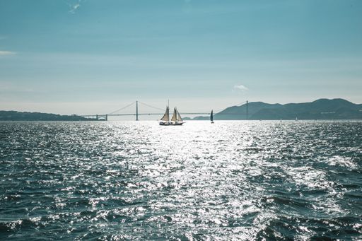 A mesmerizing shot of a sailboat on the shining sea under a blue sky on a sunny day