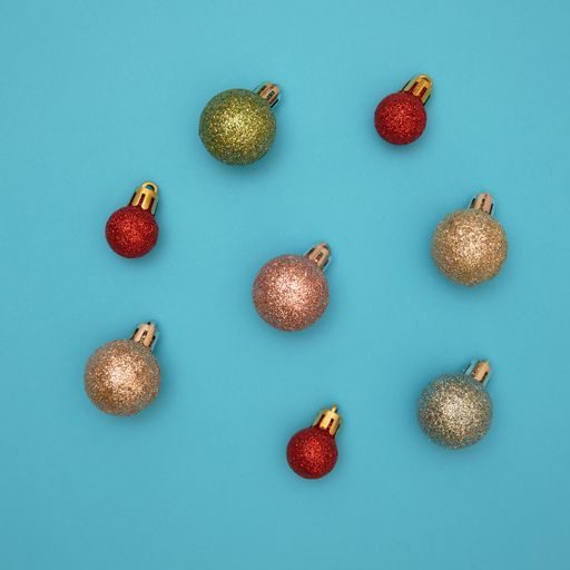 red christmas ball patterns on solid blue background. Balls of different textures and colors, some with glitter.