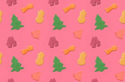 A top view of colorful Christmas cookies on a pink background