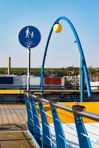 A vertical shot of a walkway over a metro overground tube in Prague with symbols against the blue sky