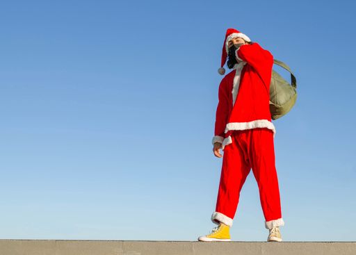 A young caucasian male wearing a Santa Claus costume and medical mask - the concept of new normal