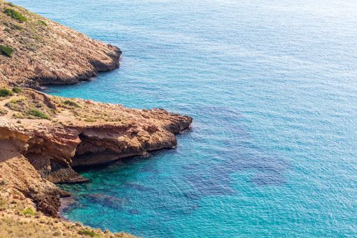 A scenic beach landscape featuring a rocky shoreline stretching out towards the clear blue waters