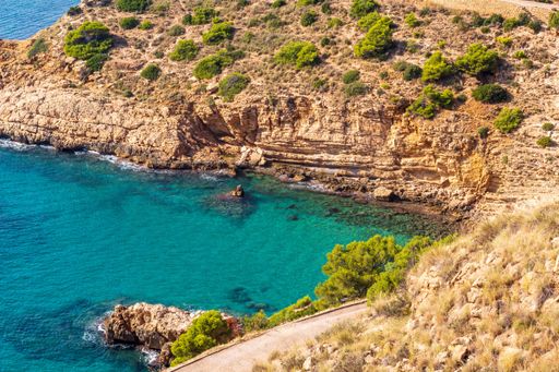 A scenic beach landscape featuring a rocky shoreline stretching out towards the clear blue waters