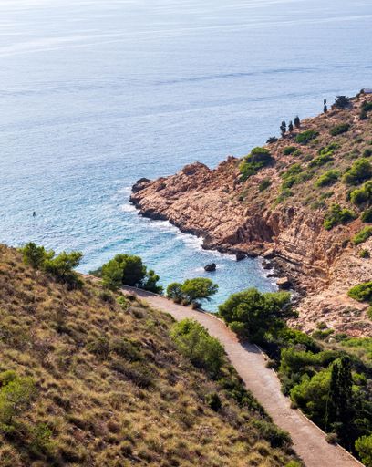 A scenic beach landscape featuring a rocky shoreline stretching out towards the clear blue waters
