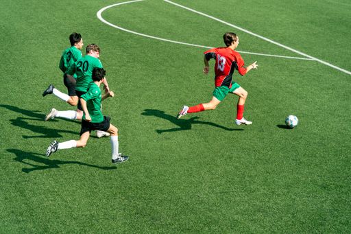 The high-angle view of a single soccer player chased by three adversaries across the field