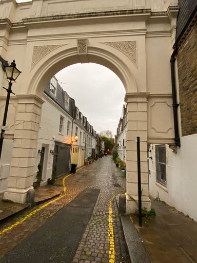 A scenic view of a bustling city street from street level, featuring a tall clock tower at the top of the image