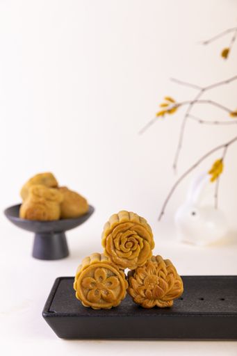 A vertical shot of mooncakes on a black plate for Mid-Autumn Festival isolated on white background