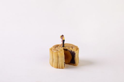 A closeup shot of kissing couple figurine on sliced mooncake isolated on white background
