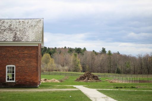 A long range shot of a brick building with ceramic roof in with a forest in the background
