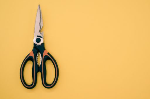 A closeup shot of scissors isolated on brown background. Cutting tool with zigzag blades, copy space