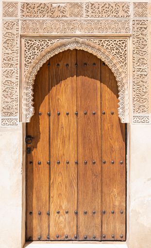 A wooden door with an archway situated at the end of a wall in an historic building
