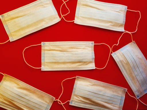 A top view of surgical protective masks laying on red isolated background. Corona pandemic