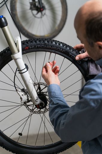A vertical shot of a European man working as a mechanic and repairing a bicycle