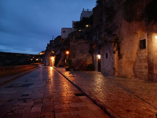 The street of the city Matera with old buildings lit by lamps at night, Italy
