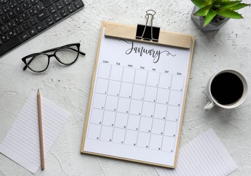 A flat lay of the calendar of January, glasses, coffee and other objects for working -  background