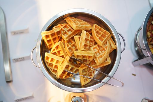 A top view of a metallic bowl filled with belgian waffle on a white table