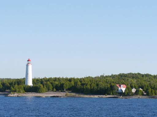 A shot of a lighthouse near the water under the clear sky