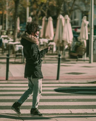 A shallow focus shot of an attractive Latina with a scary face mask crossing the road