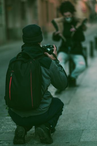 A vertical selective focus shot of a photographer taking photos of a woman