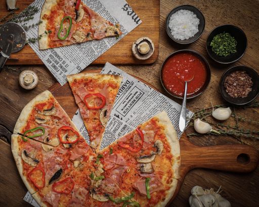 The flat lay of a delicious Italian pizza, sauce, spices on a table
