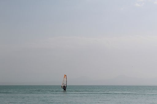 A beautiful shot of a sailor on the open sea, correcting the sail of the boat. Silhouette of the m