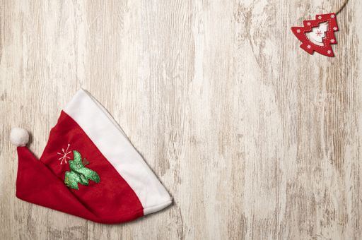 A top view of a Santa Claus hat and a red little wooden Christmas tree on the top left corner