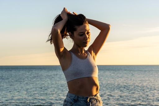 A selective focus shot of an attractive female posing on a beach on a sunny day in Benicassim, Spain