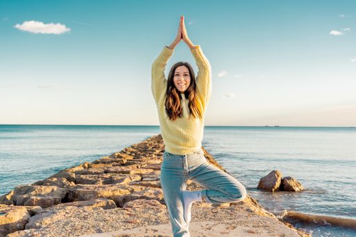 A selective focus shot of an attractive female in a yoga pose on a beach in Benicassim, Spain