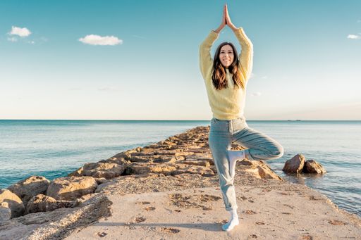 A Caucasian female doing yoga on a beach in Benicasim, Spain