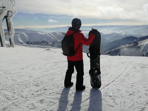 A mesmerizing view of beautiful snow-capped mountains with a snowboarder in the foreground