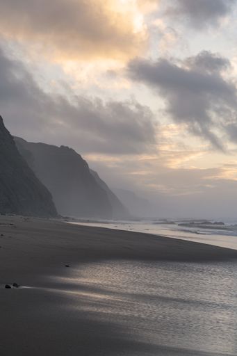 A vertical shot from a sandy beach facing the clear sea and cloudy sky - perfect background