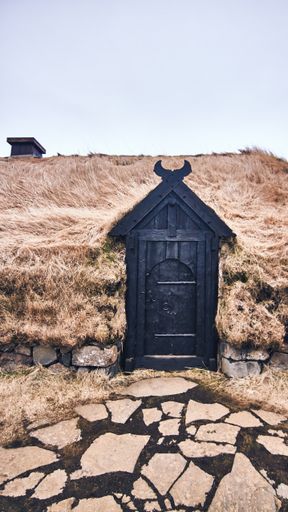 A vertical shot of a traditional old Viking house with a black door in front in Iceland